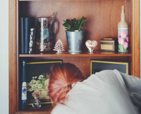 Spring Cleaning Tips in Time for Your Move 1 Woman Cleaning Book Shelf | 3GuysMoving.com